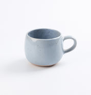 Handmade blue speckled ceramic mug on a white background