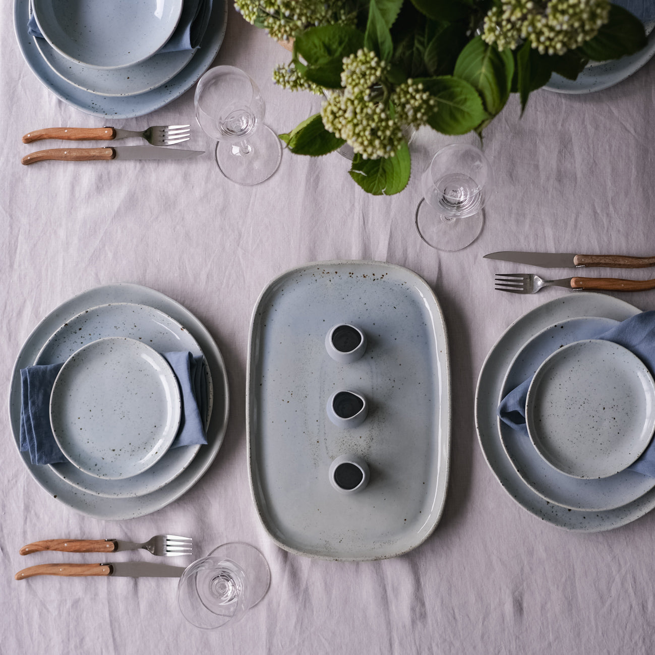calming dinnerware set and table setting with fresh flowers by Palinopsia Ceramics on a grey linen tablecloth