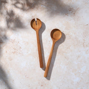 Bird’s-eye view of a retro teak wooden salad serving set by Palinopsia on a light stone background.