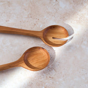 Detailed shot of a retro teak wooden salad serving set by Palinopsia on a light stone background.
