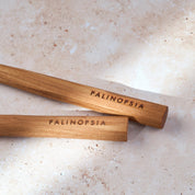 Close-up shot of the handles of teak wooden salad servers with Palinopsia labels on the handles.