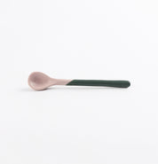 Ceramic spoon with a green handle and pink tip on a white background