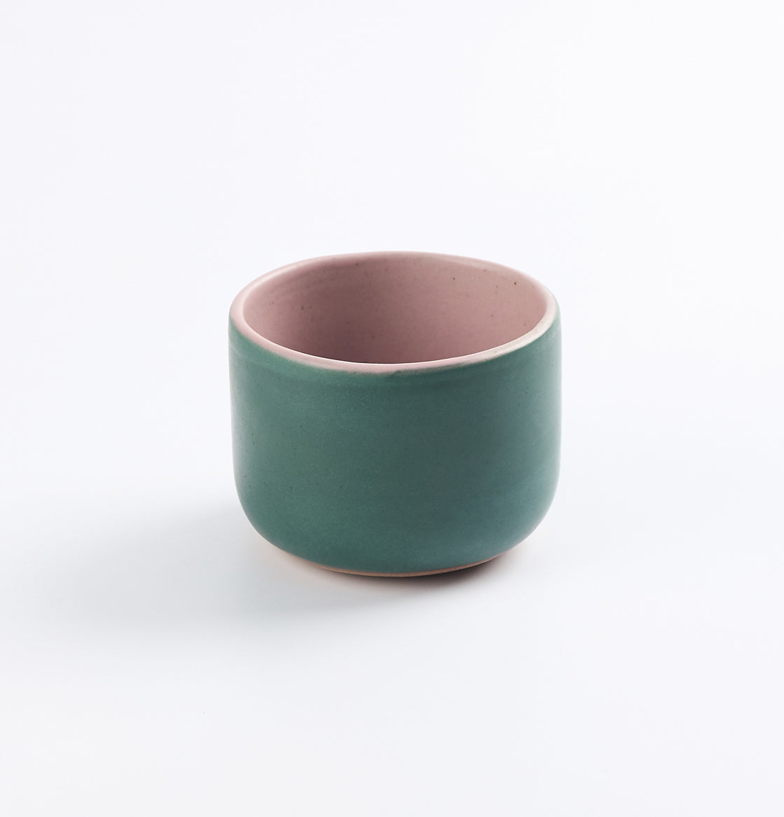 Palinopsia&#39;s green ceramic stoneware cup with pink interior on a white background