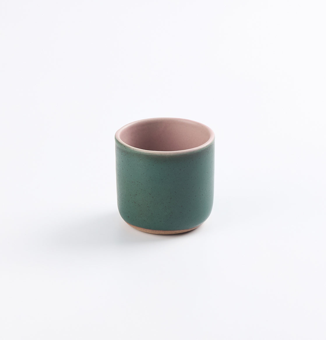 Green stoneware ceramic cup with pink interior on a white background
