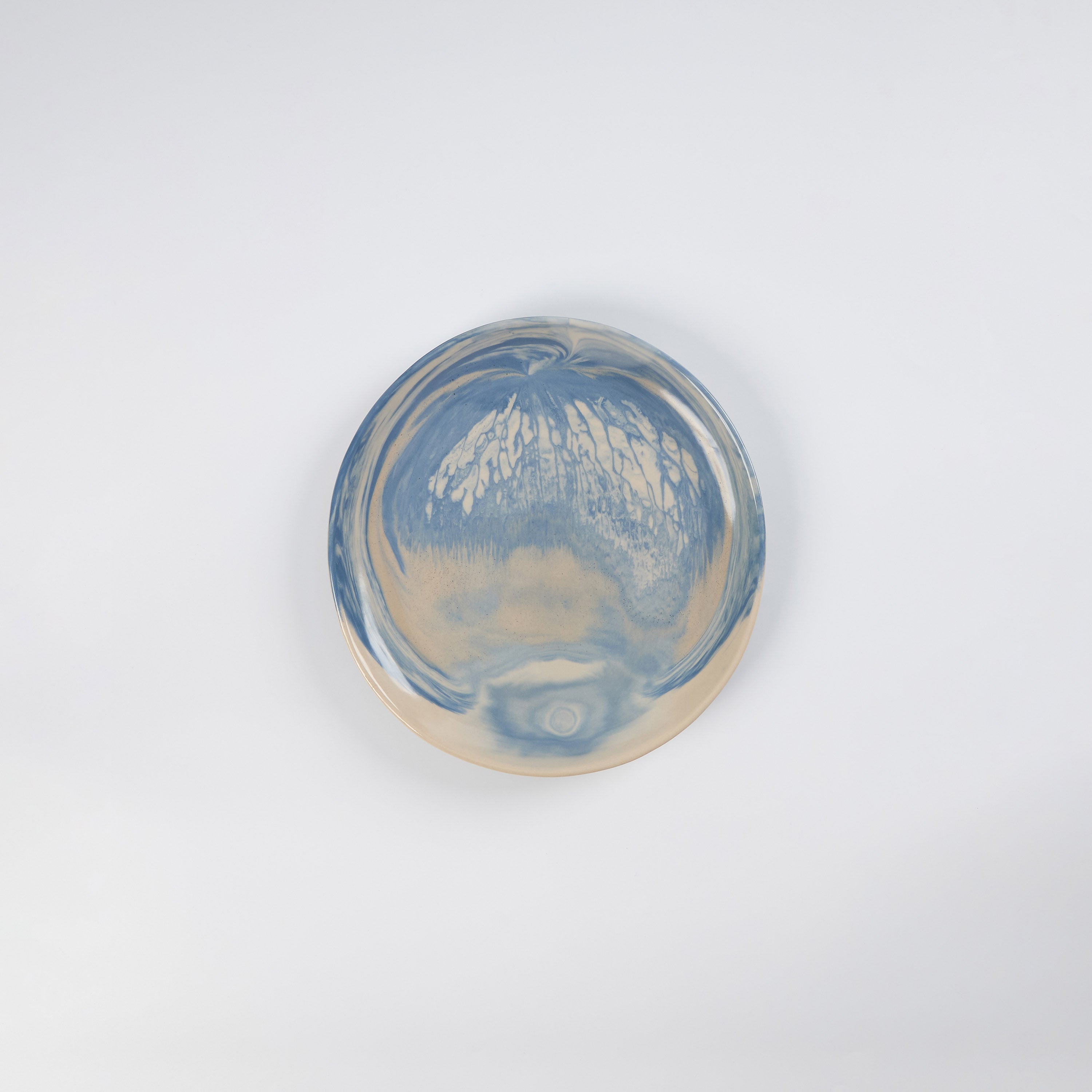 Small handmade ceramic plate with a marbled clay pattern in cobalt blue, beige and cream on a white background by Palinopsia