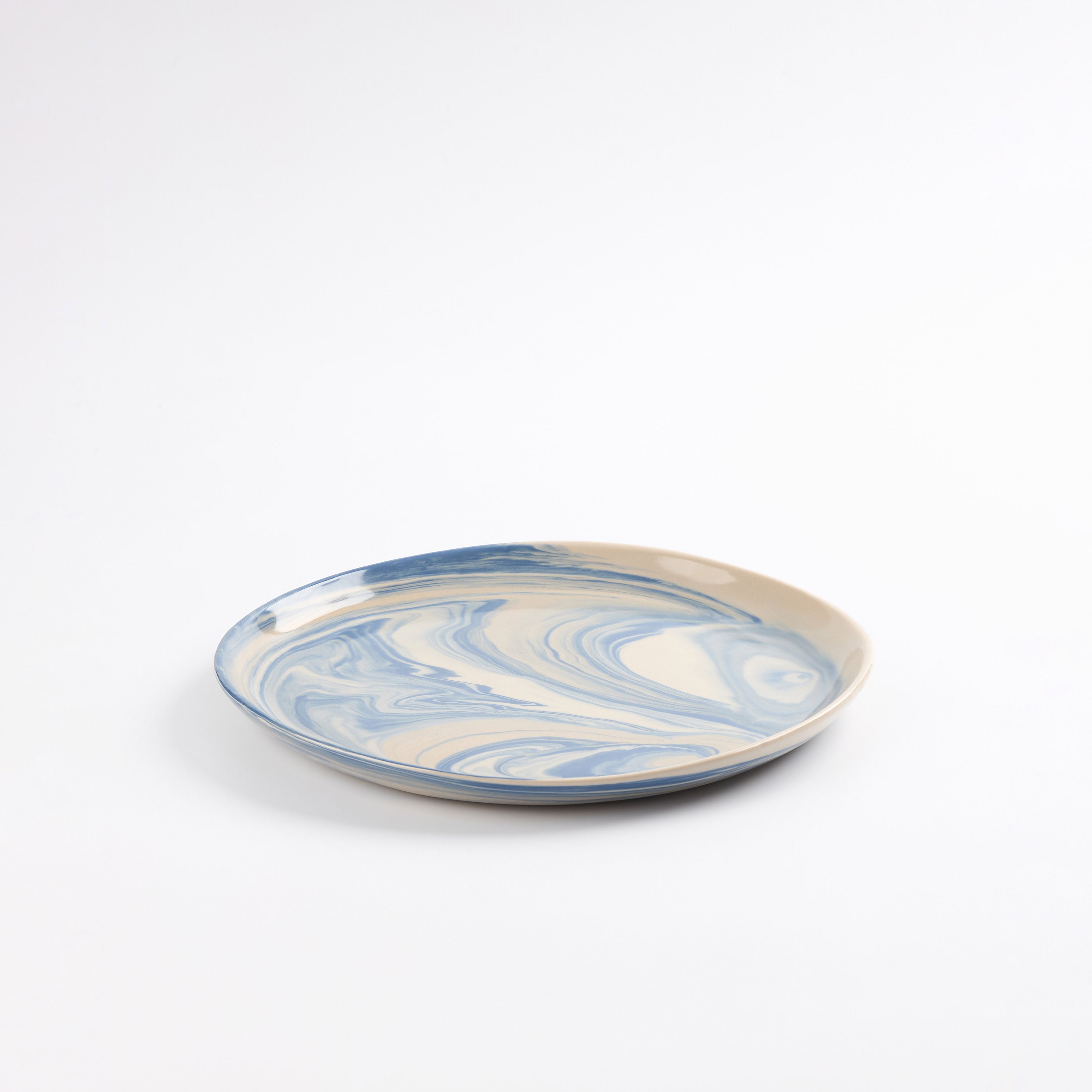 Handmade ceramic plate with a marbled clay pattern in cobalt blue, beige and cream on a white background by Palinopsia