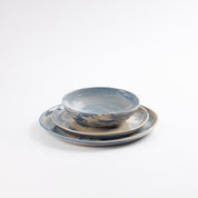 Three piece handmade ceramic dinner set with a marbled clay pattern in cobalt blue, beige and cream on a white background by Palinopsia