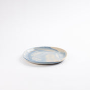 Small handmade ceramic plate with a marbled clay pattern in cobalt blue, beige and cream on a white background by Palinopsia