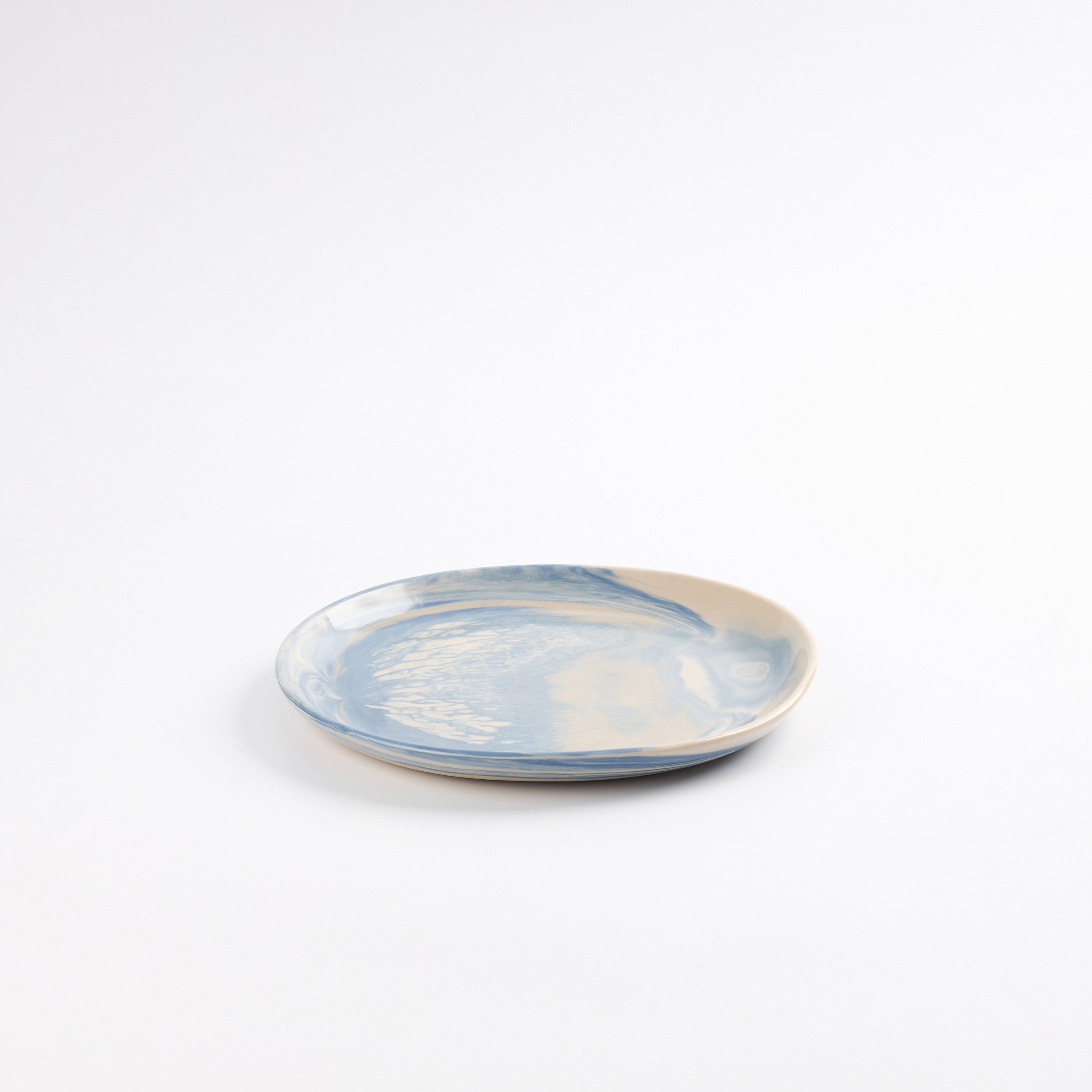 Small handmade ceramic plate with a marbled clay pattern in cobalt blue, beige and cream on a white background by Palinopsia