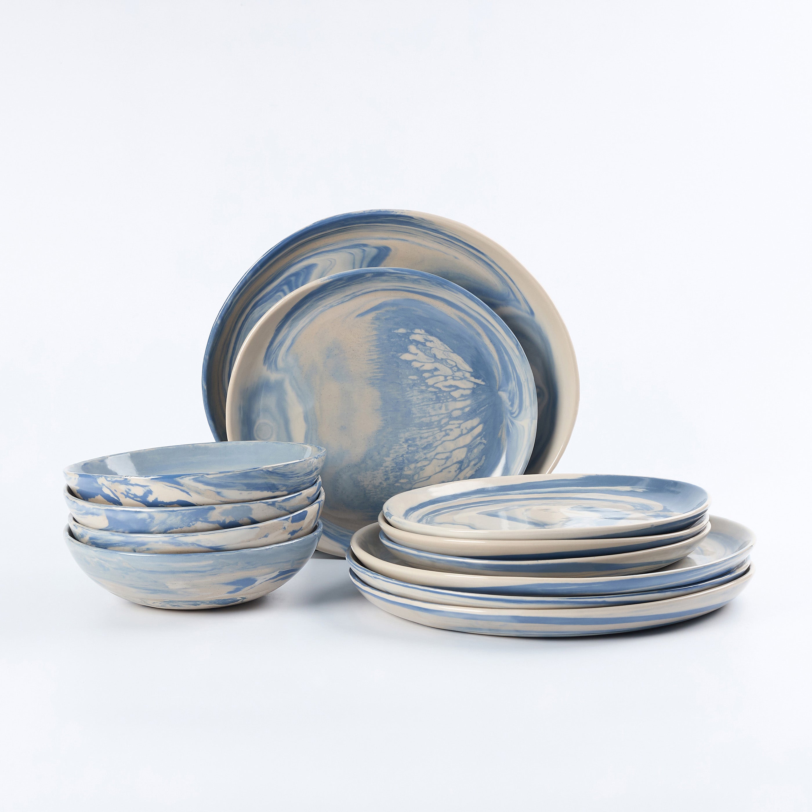 Three piece dinner set of handmade ceramics with a marbled clay pattern in cobalt blue, beige and cream on a white background by Palinopsia