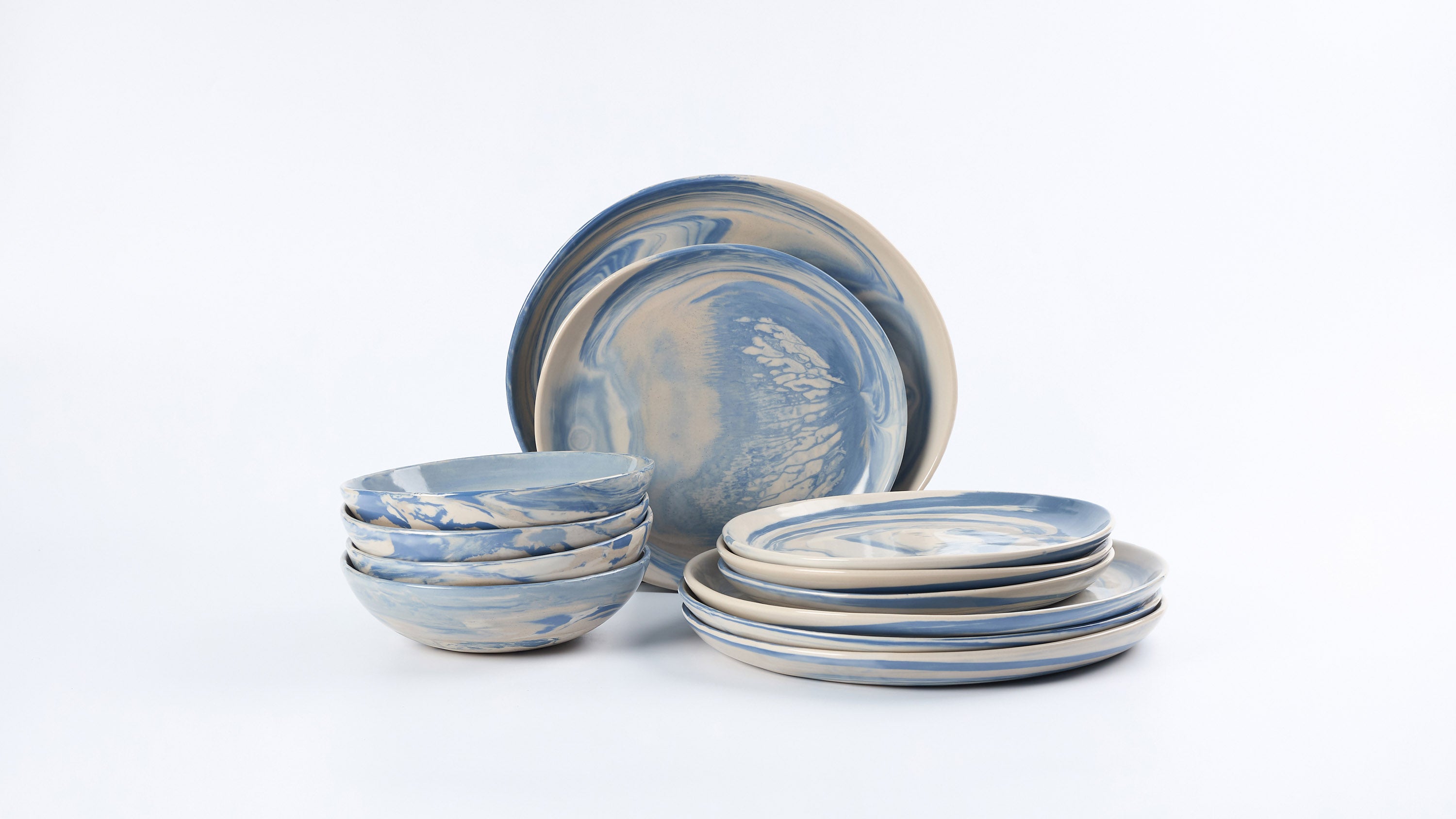 Dinner Set of Palinopsia ceramic plates and bowles with blue and white marbled design on a white background