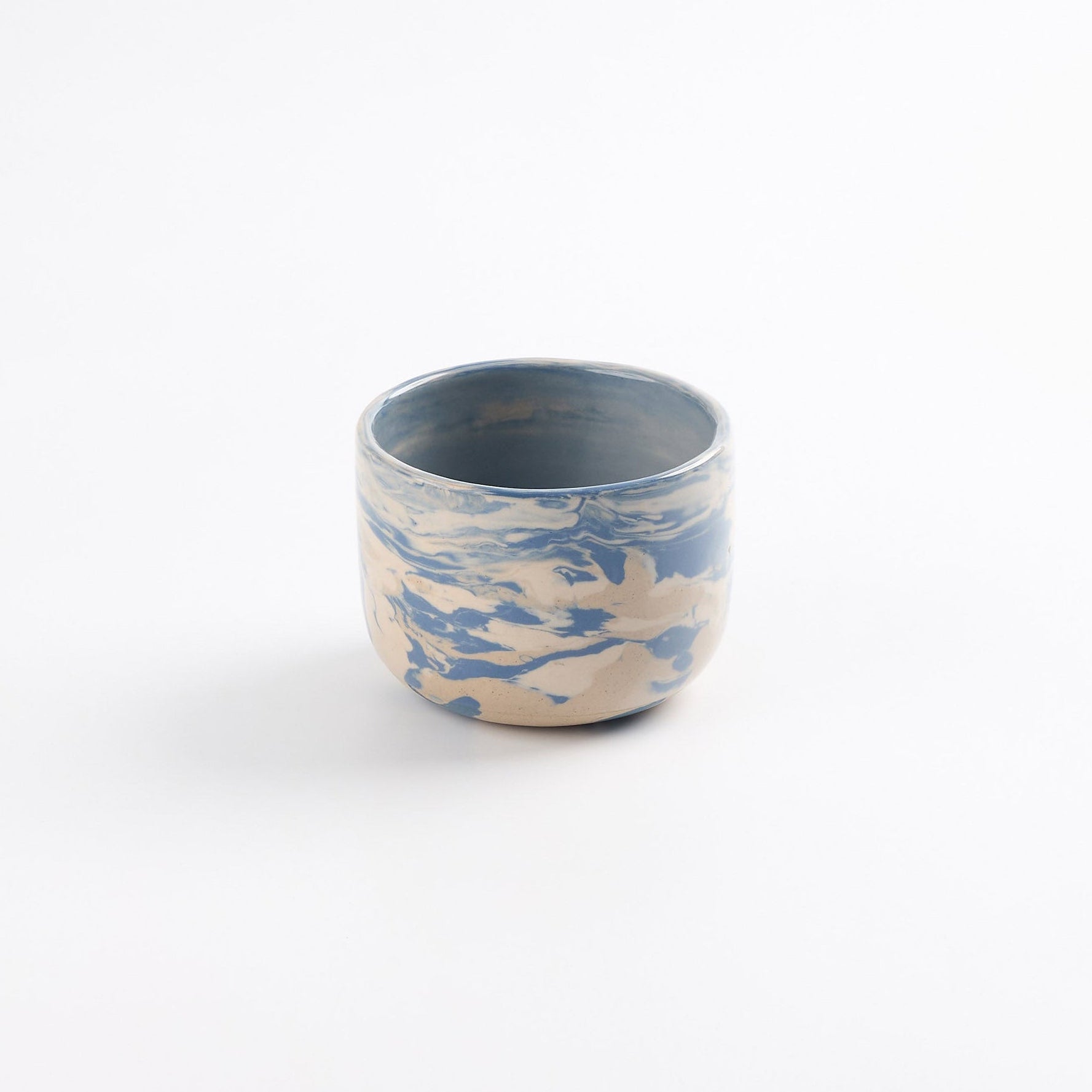 Tumbler ceramic cup with a blue and white marbled pattern on a white background