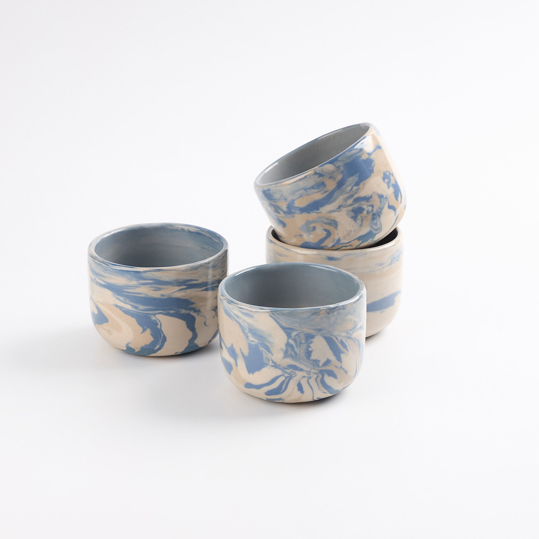 Set of ceramic cups with blue, white and beige marbled pattern on a white background