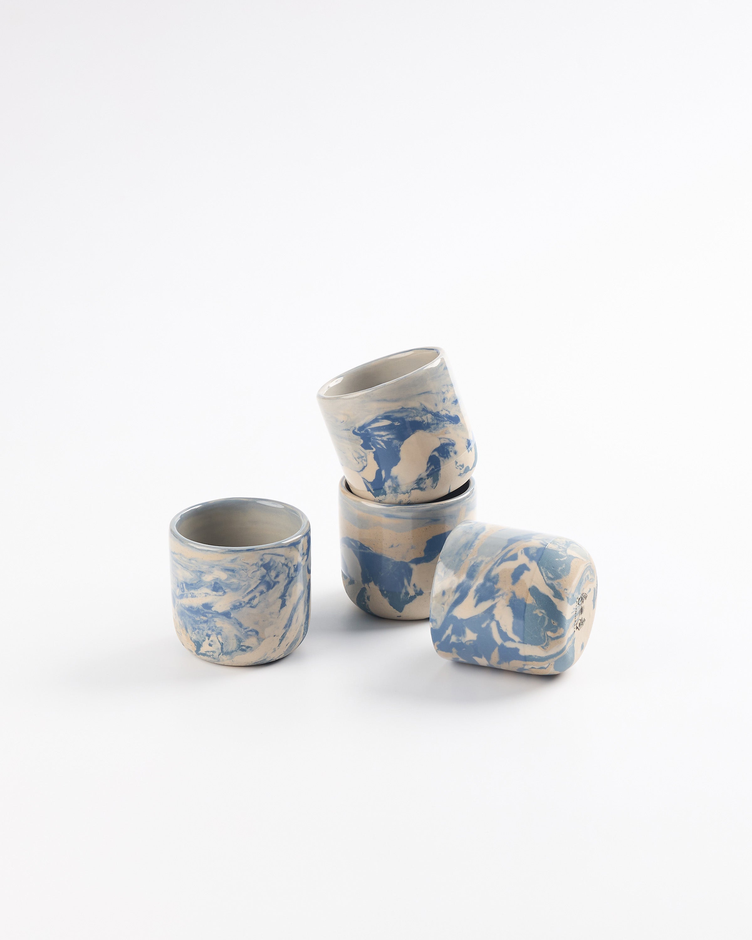 Set of blue and white ceramic espresso cups with cobalt blue marbled design on a white and beige background