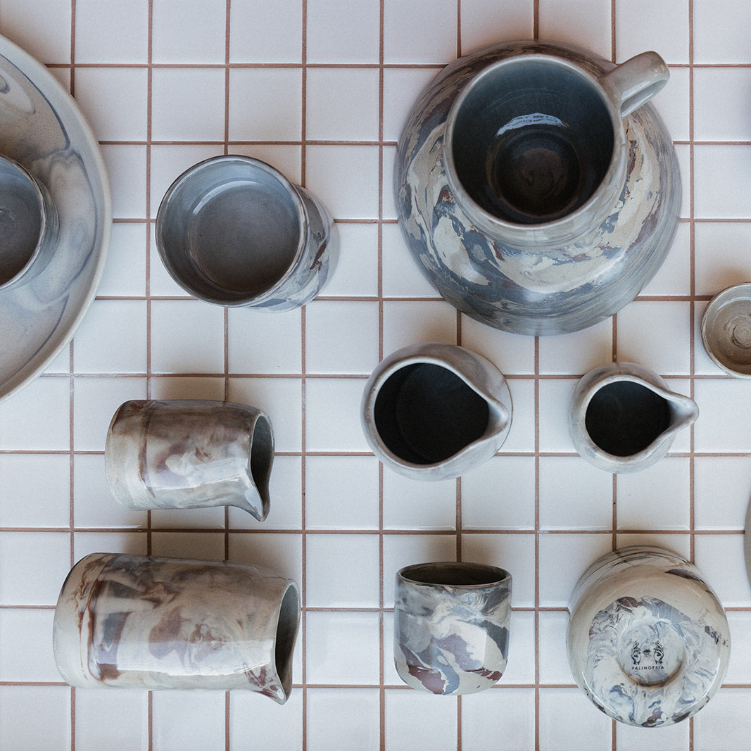 Palinopsia Marbled clay ceramic dinnerware mugs cups and hand pourers on tiled kitchen bench