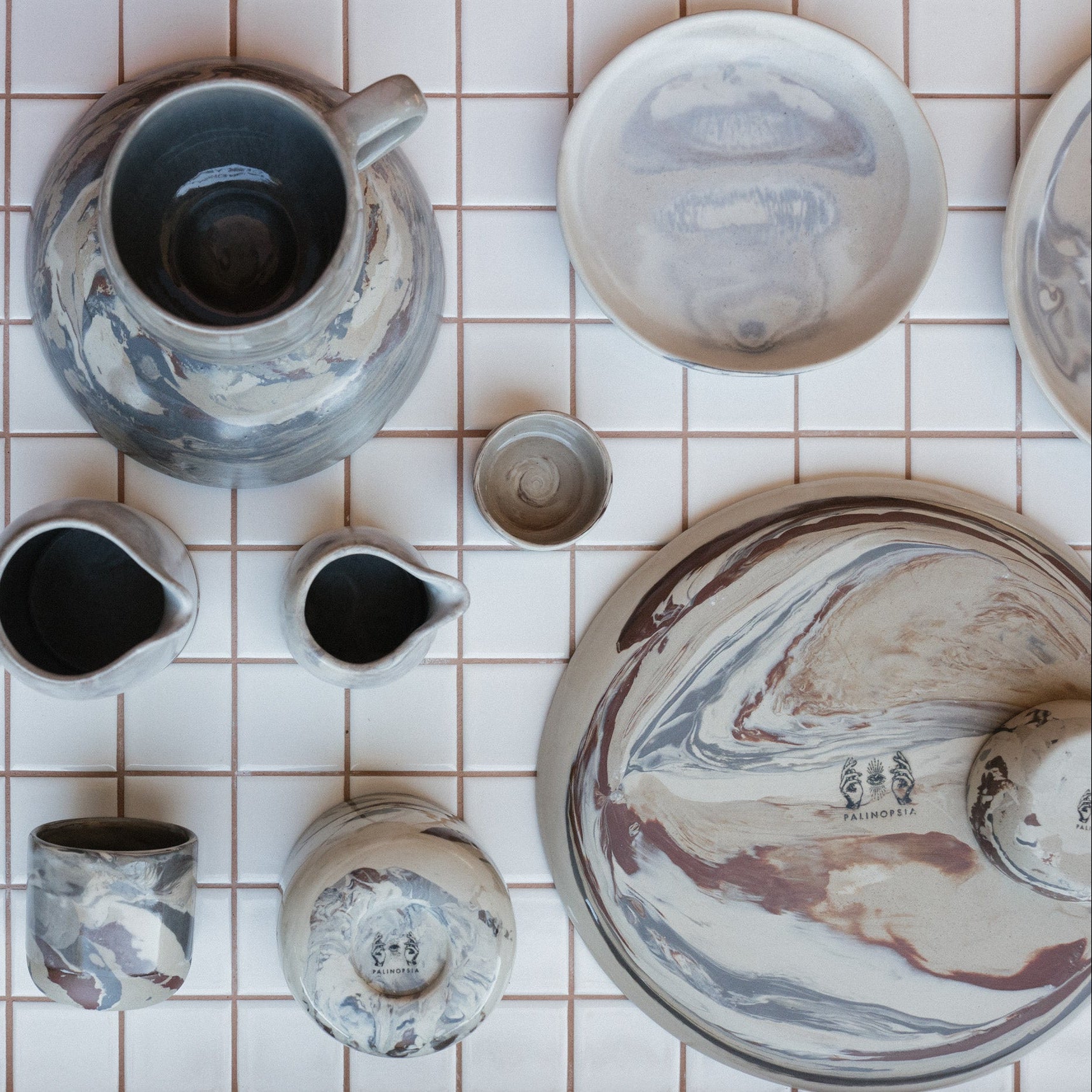 Palinopsia marbled clay full dinner set with hand pourers and mugs on kitchen bench 