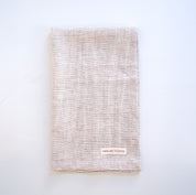 Textured linen tea towel with a brand label on a light gray background