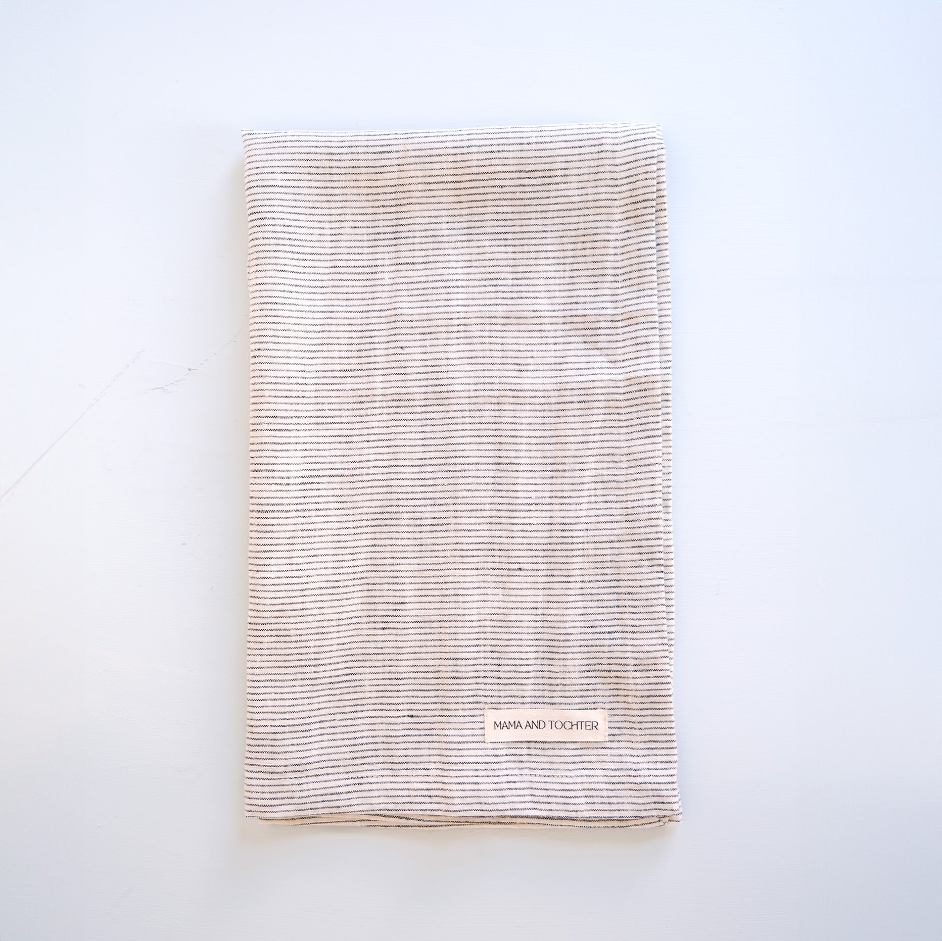 Textured linen tea towel with a brand label on a light gray background
