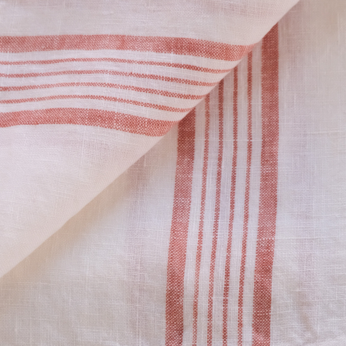 Close-up of red striped linen tea towel fabric on a white background