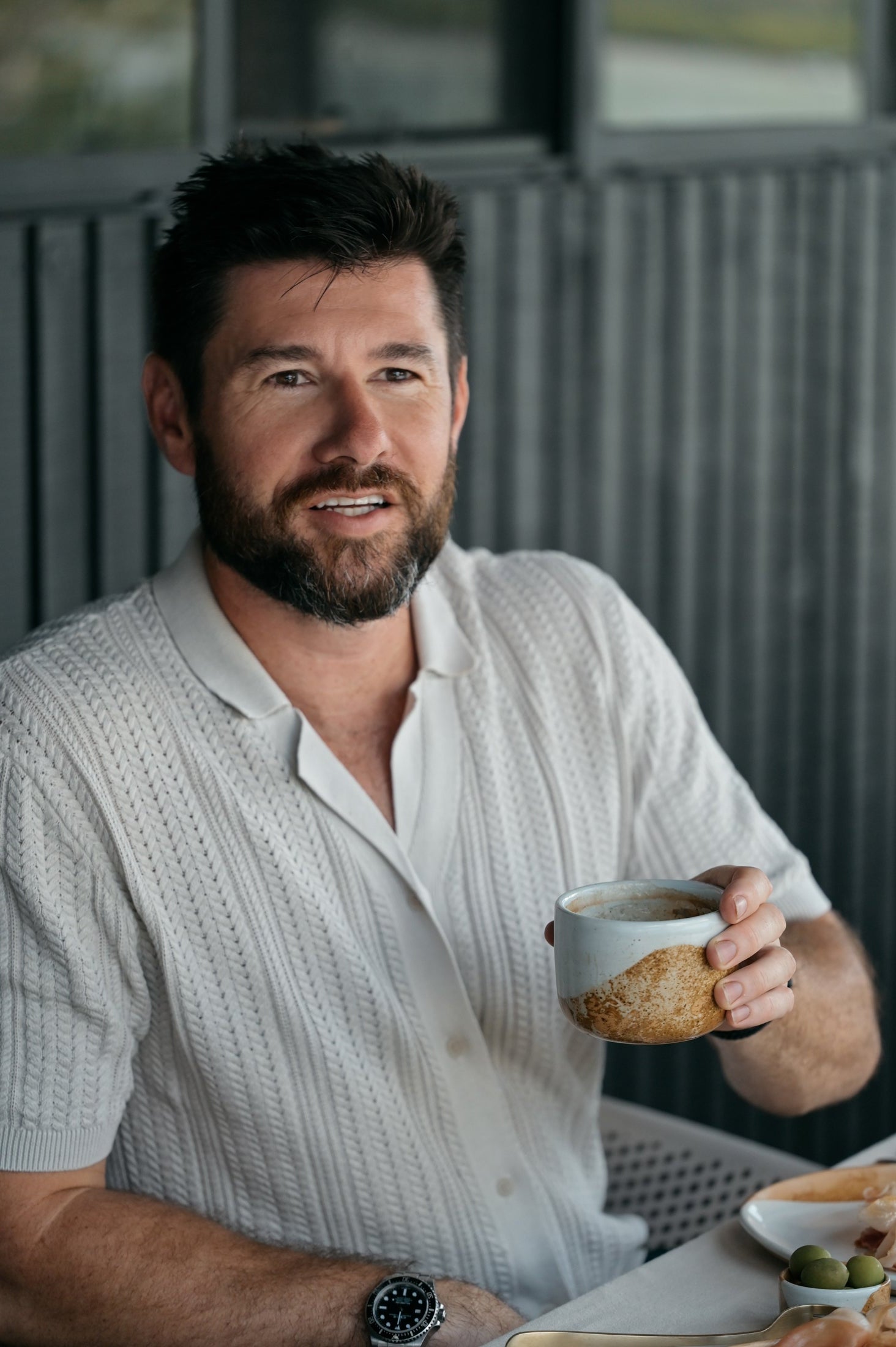 Man enjoying breakfast and holding a Palinopsia coffee cup 