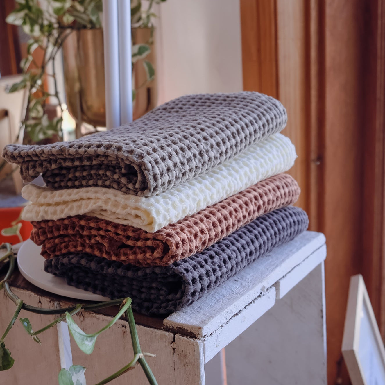 Stack of folded textured waffle tea towels on a white surface with a blurred indoor background