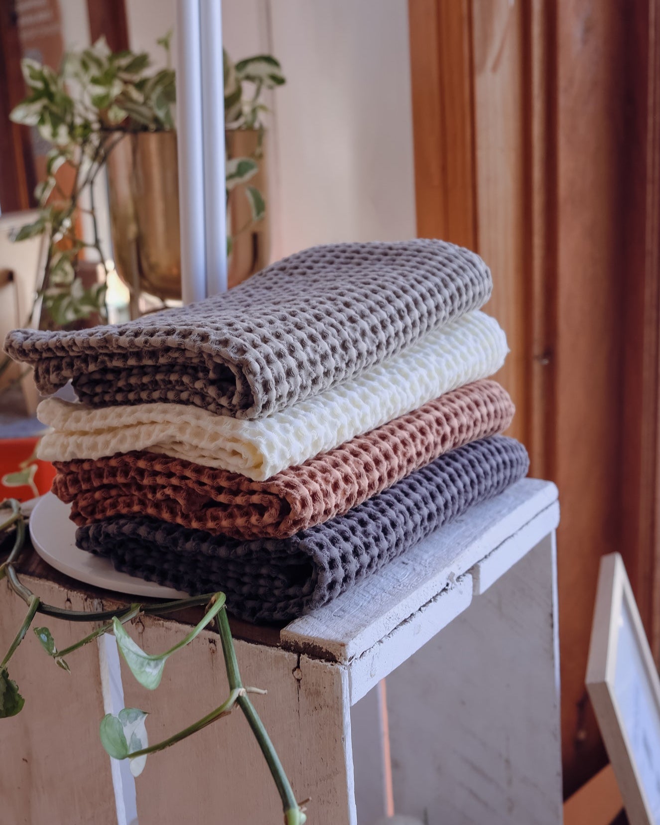 Stack of folded textured waffle tea towels on a white surface with a blurred indoor background
