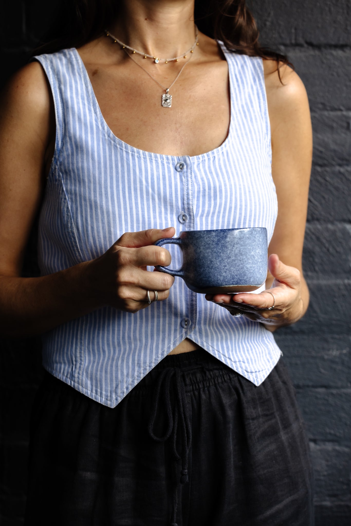 Woman holding a blue and white stoneware mug against a dark background