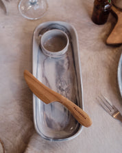 A rectangular ceramic serving dish with a grey, red and white marble pattern, featuring a small matching ramekin inside. A light wood-handled knife with 'PALINOPSIA' engraved on the handle rests on the tray.