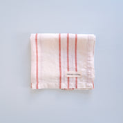 Folded linen tea towel with red stripes on a light blue background