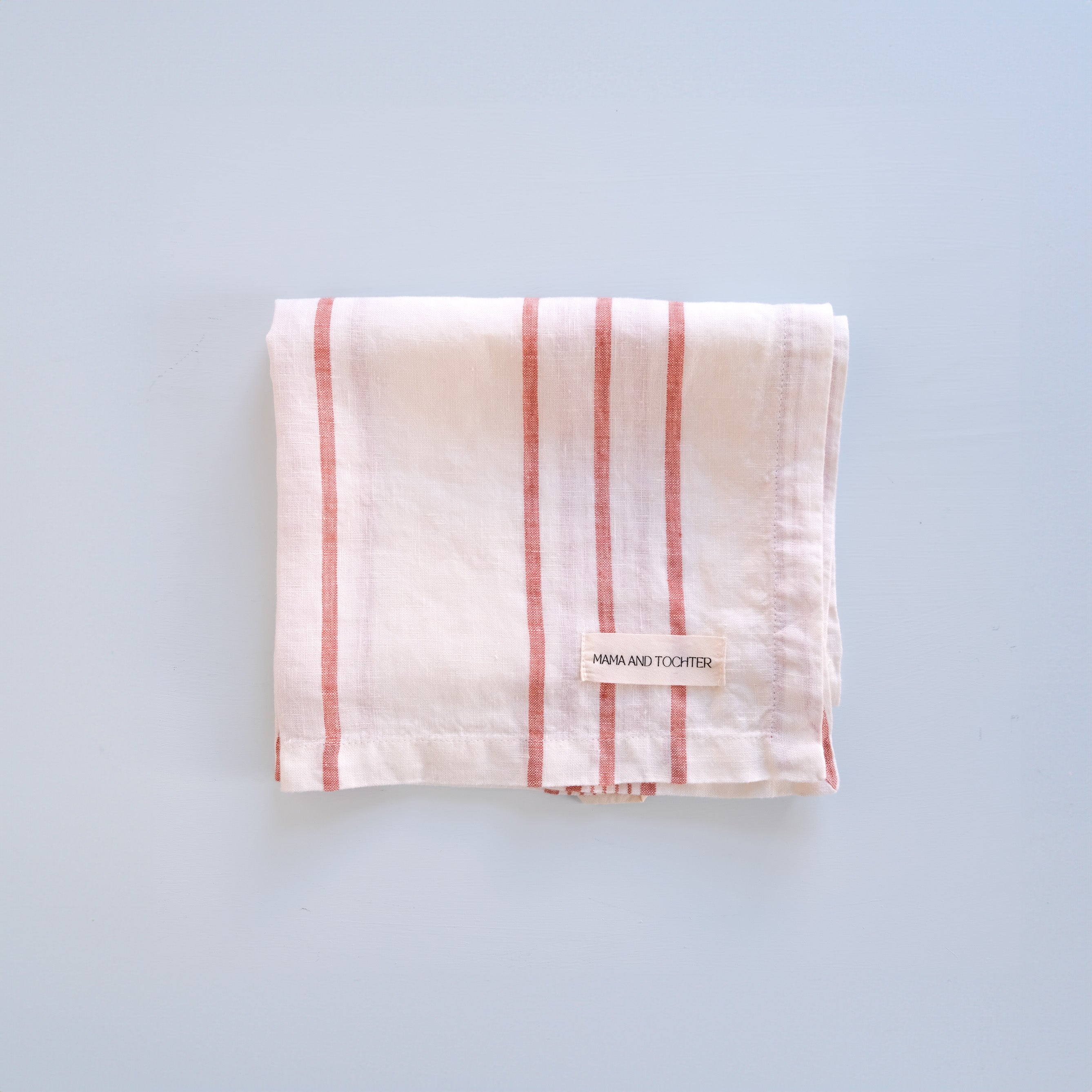 Folded linen tea towel with red stripes on a light blue background