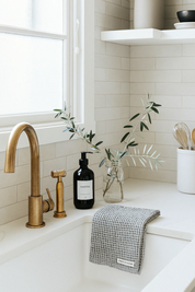 Bathroom with brass faucet, black soap dispenser, and waffle tea towel in light grey.