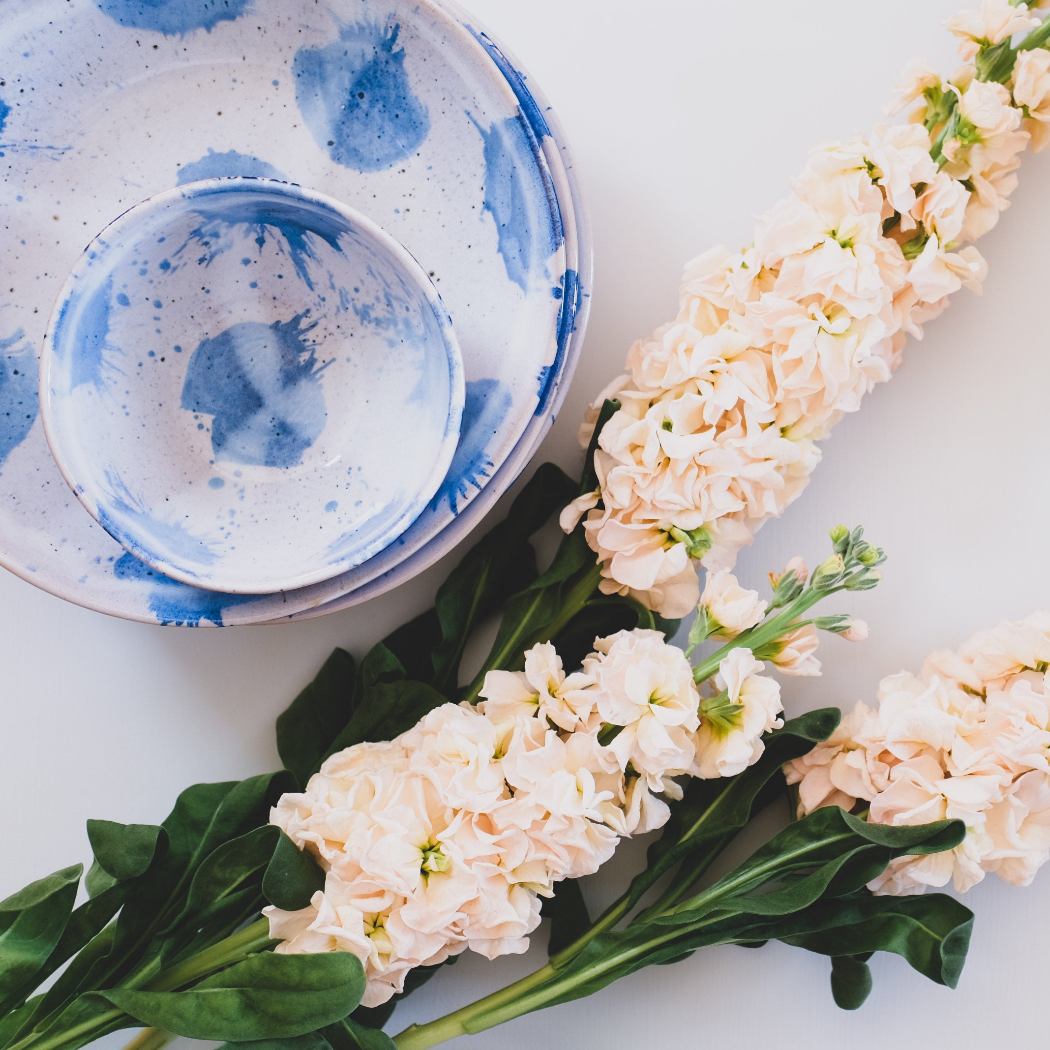 Bird's-eye view of handmade blue and white pasta bowls and breakfast bowl with wild flowers by Palinopsia 