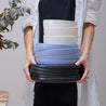Woman holding a stack of handmade pasta bowls and black dinner plates by Palinopsia Ceramics in Sydney Australia 