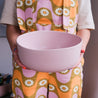 Girl with bright jumpsuit holds a handmade fruit bowl in powder pink at Palinopsia Ceramics in Newcastle