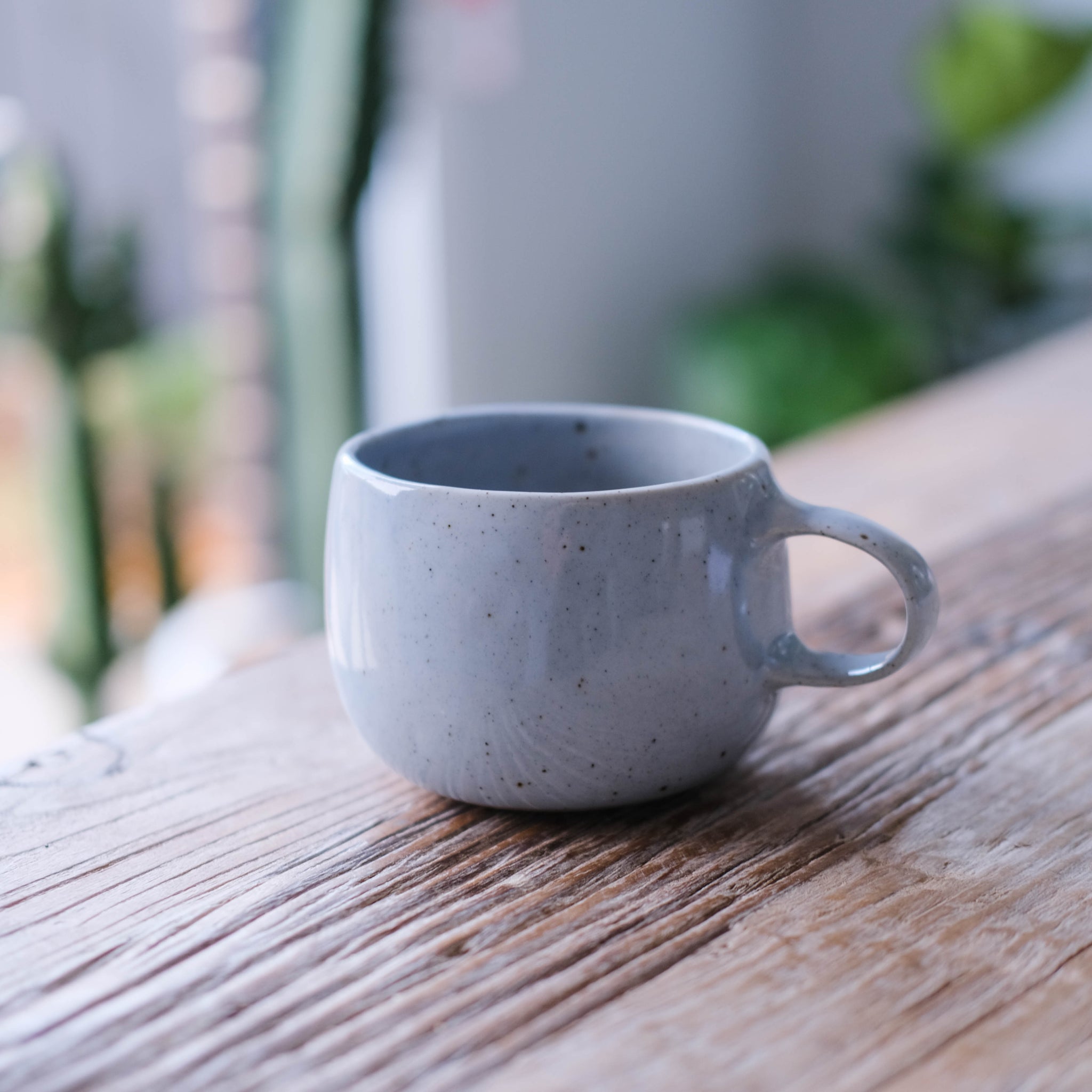 A handmade Palinopsia blue coffee mug on a timber table top 