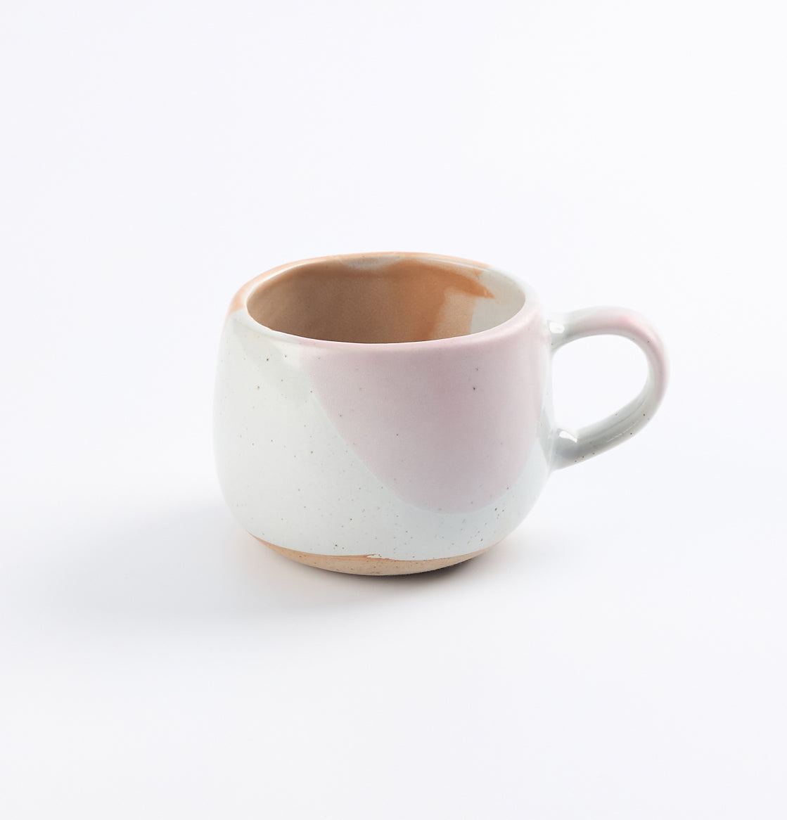 Handmade stoneware ceramic mug with a pinkish hue and chocolate glaze drips on a white background