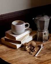 Ceramic mug and teaspoon with a Bialetti Moka styled on reading books 