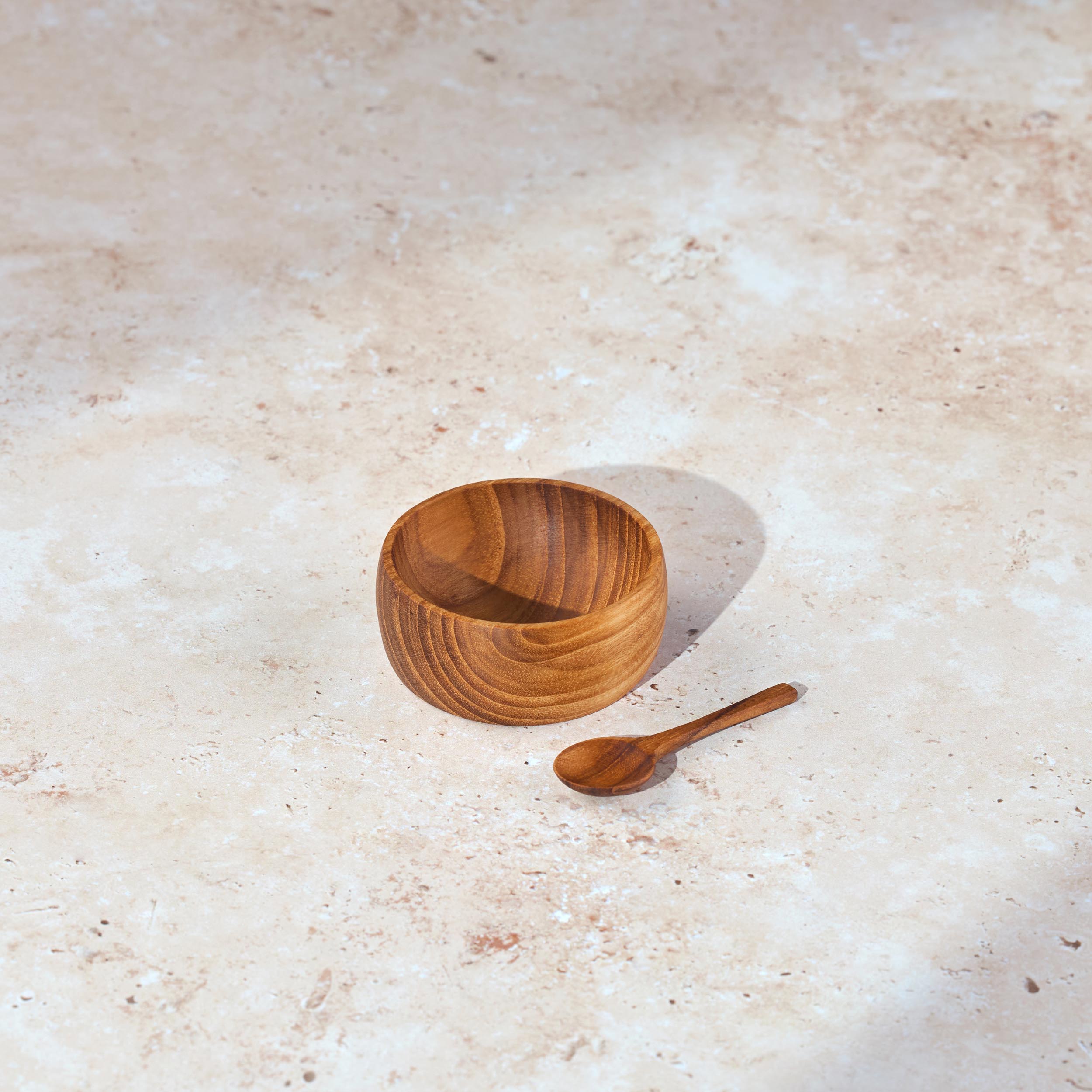 Small Palinopsia wooden teak salt bowl with matching spoon on a stone bench top 