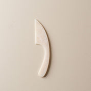 White and light pink resin cheese knife on a beige background