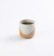 Ceramic stoneware cup with two-tone soda fired in blue and brown design on a white background