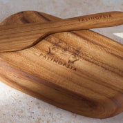 Detailed shot of a small teak wooden tray and knife with the Palinopsia logo on the bottom.