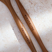 Close-up shot of the handles of large teak wooden salad servers with Palinopsia labels on the handles.