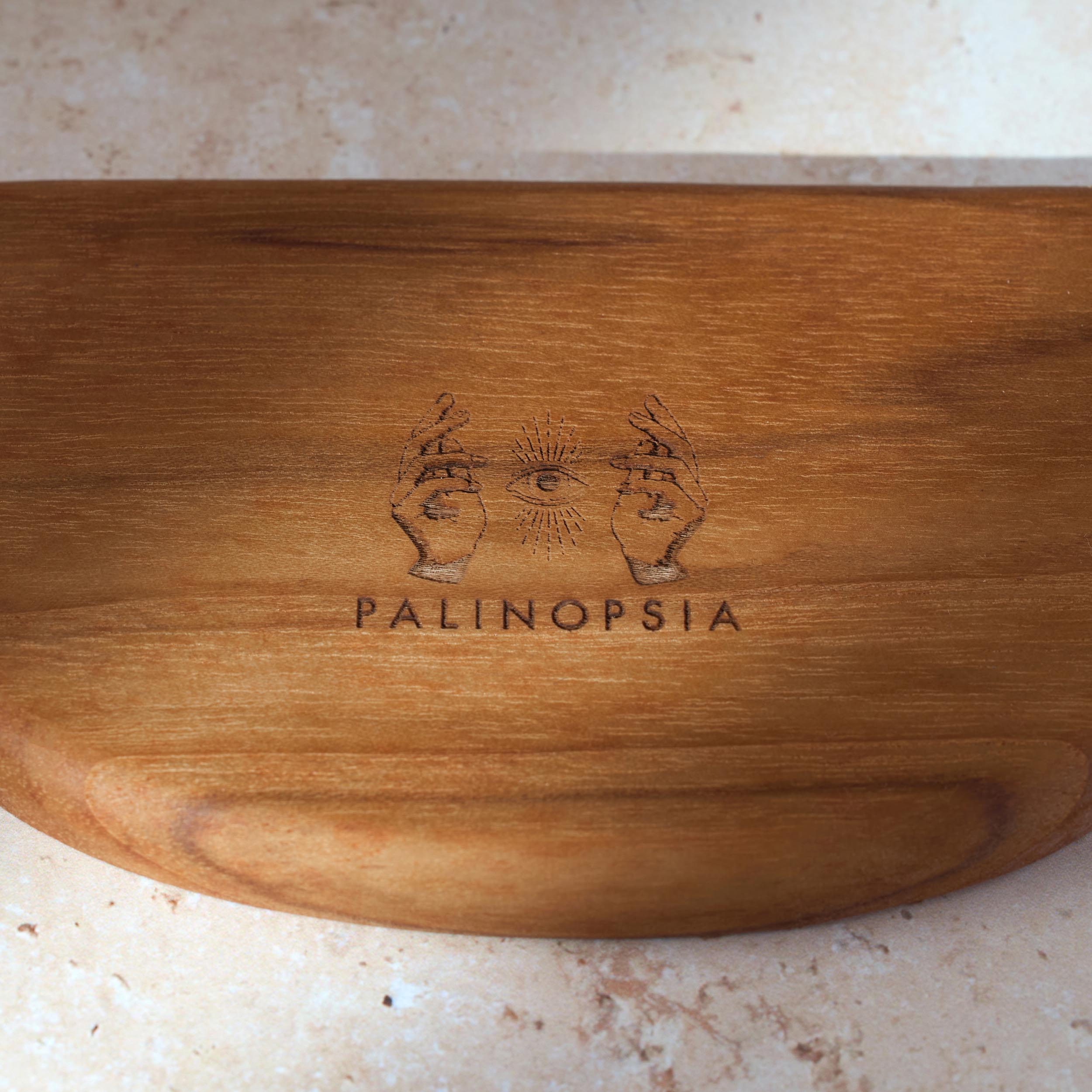 Detailed shot of teak wooden serving tray with the Palinopsia logo on the bottom.