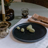 Table setting by  Palinopsia Ceramics displaying their Australian made linen collection of table cloths, placemats and napkins with a black handmade plate and still life setting in Sydney Australia 