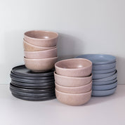 Handmade dinner set by Palinopsia ceramics showing how the pieces are stacked which includes a black dinner plate, blue pasta bowl and a mushroom grey soup bowl 