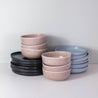 Side view of a stack of handmade dinner plates and bowls for 6 people by Palinopsia ceramics in Sydney Australia showing their dinner set in block colours of blue, black and greys