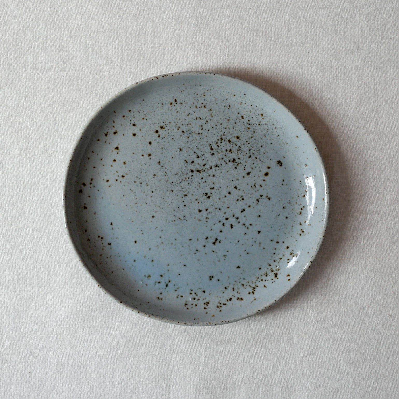 Bird's-eye view of a lunch plate by Palinopsia Ceramics on a white linen tablecloth 