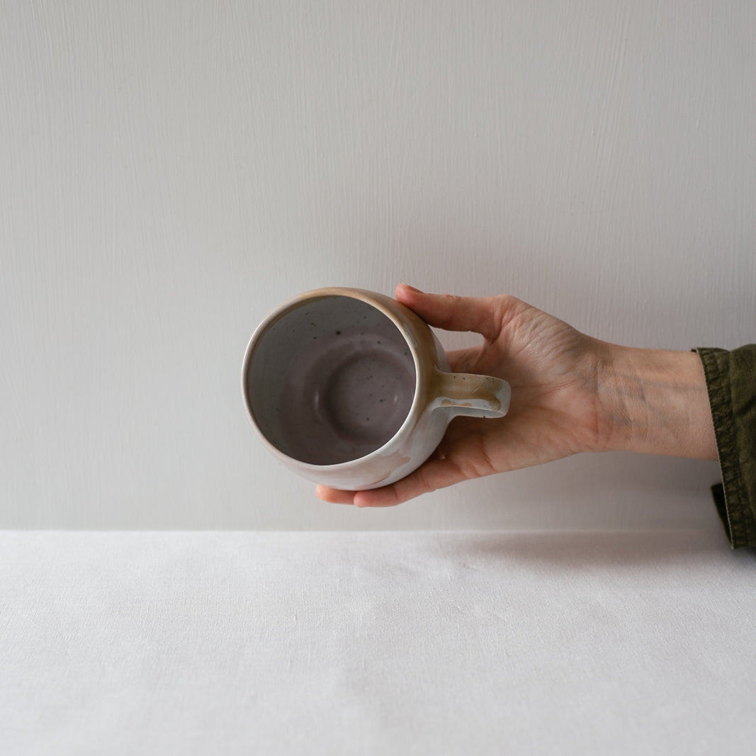 Hand holding out a handmade stoneware mug