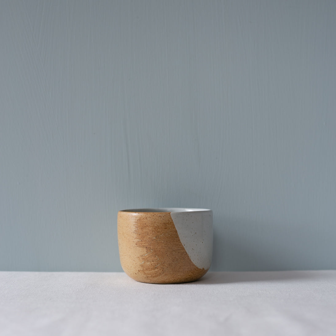 A single ceramic coffee cup without handle in blue and brown by Palinopsia