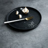 Handmade Black dinner plate by Palinopsia Ceramics in Newcastle with garlic salt in a moody still life setting 